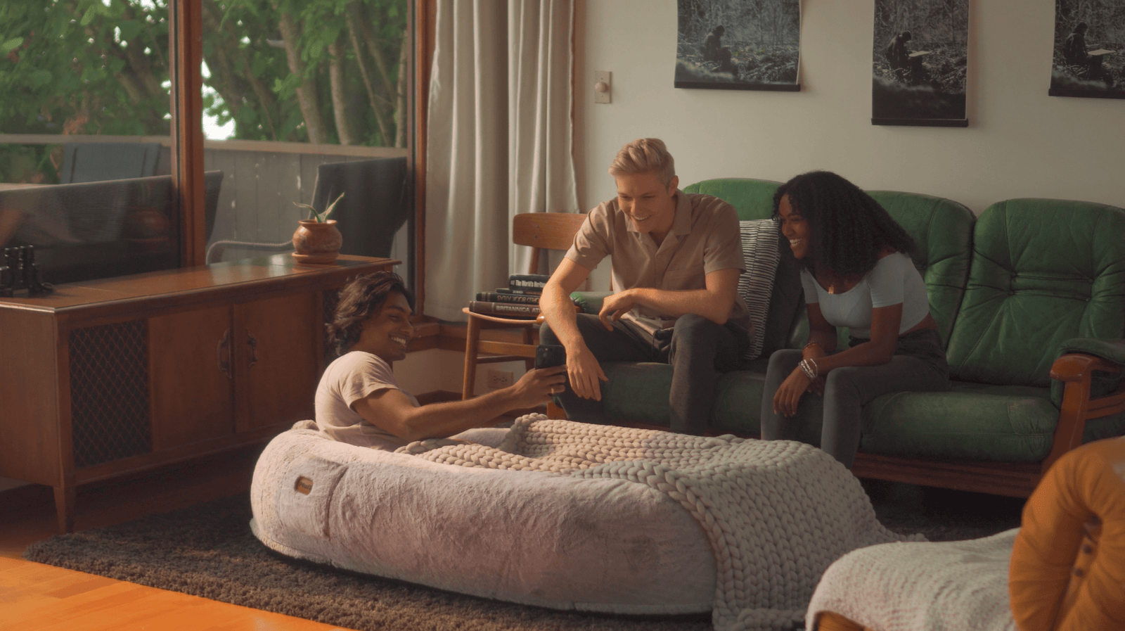 Three friends huddled over the Plufl: the world's first dog bed for humans, looking at phone
