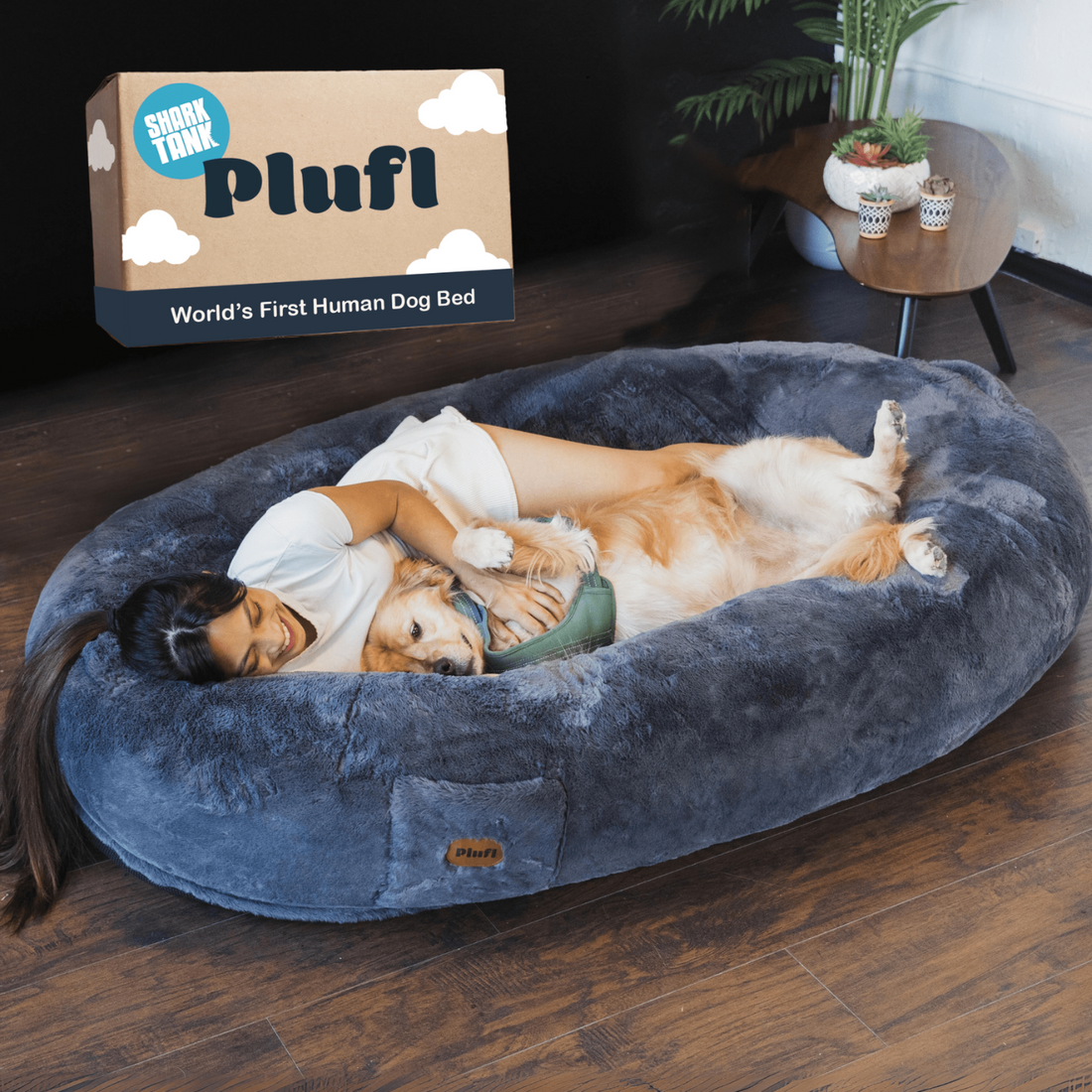Person cuddling with a dog in a large, cozy bed labeled 'World’s First Human Dog Bed.'