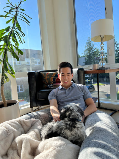 A good looking guy playing with his dog and sitting on the super soft human-sized dog bed from Plufl