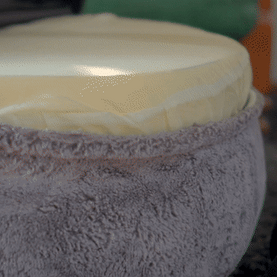 Soft, round cushion with a plush fabric cover.