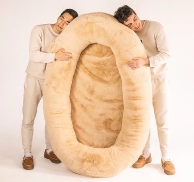 Plufl founders holding giant cozy human dog bed
