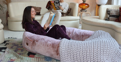 Woman reading a book in comfy Plufl: world's first human dog bed
